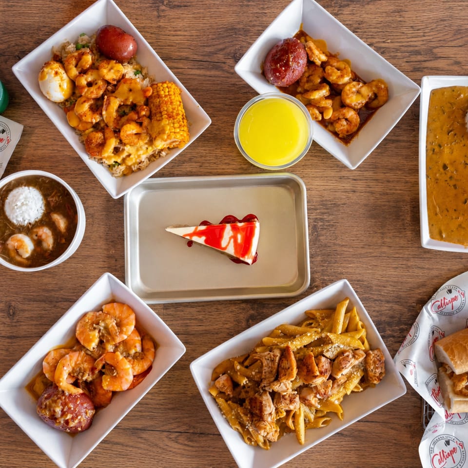 Overhead spread of seafood dishes featuring shrimp, rice, pasta, sandwiches, dessert, dipping sauces, and sides on a wooden table.